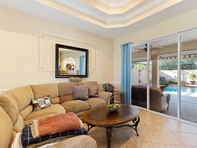 living room featuring a tray ceiling, tile patterned floors, ceiling fan, and crown molding