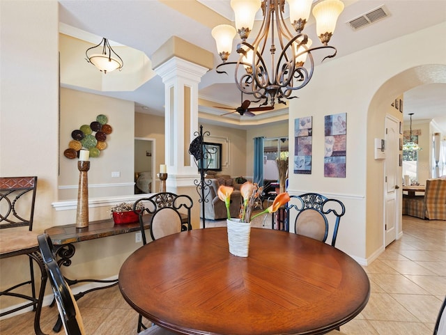 tiled dining space with an inviting chandelier, ornamental molding, and ornate columns