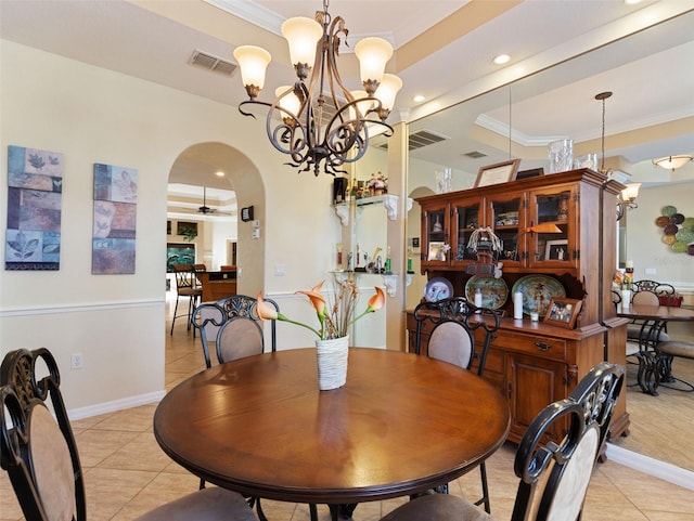 tiled dining space featuring ceiling fan with notable chandelier, ornamental molding, and a tray ceiling