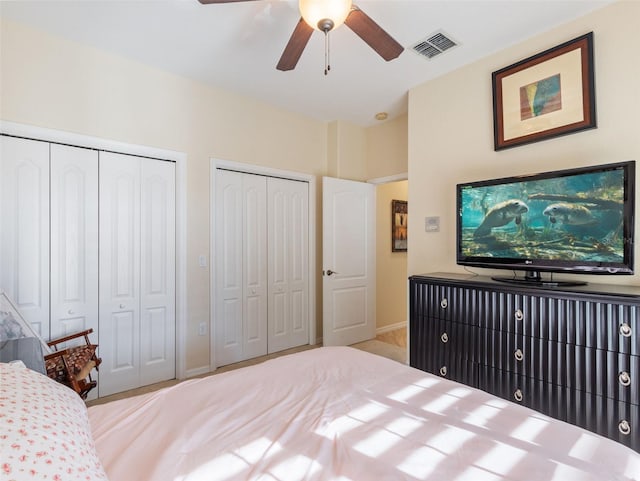 bedroom with ceiling fan and multiple closets