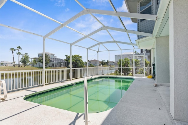 view of pool with a water view, glass enclosure, and a patio area