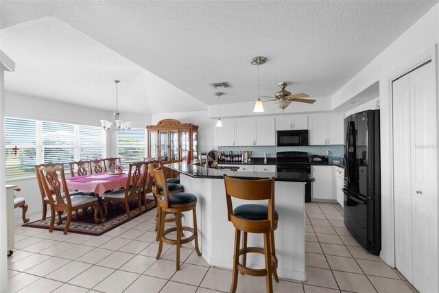 kitchen with backsplash, white cabinetry, black appliances, and ceiling fan with notable chandelier