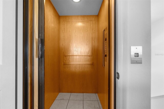 hallway with elevator and light tile patterned floors