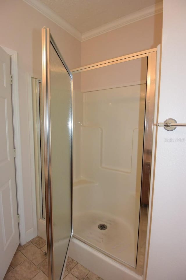 bathroom with tile patterned floors, a shower with door, and crown molding