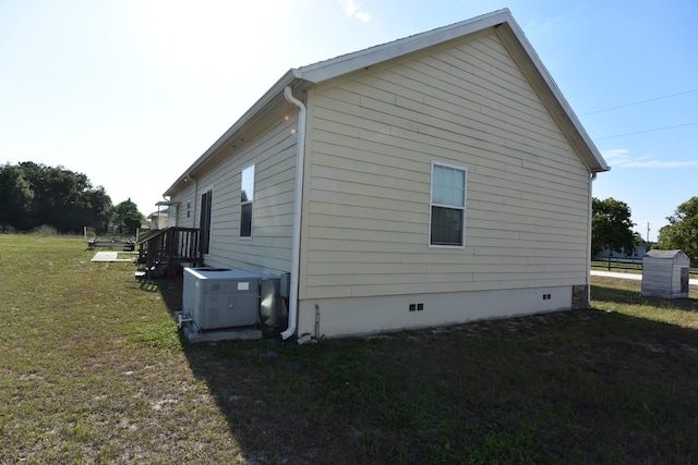 view of side of home featuring central AC and a lawn