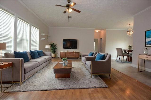 living room with hardwood / wood-style floors, ceiling fan with notable chandelier, ornamental molding, and a textured ceiling