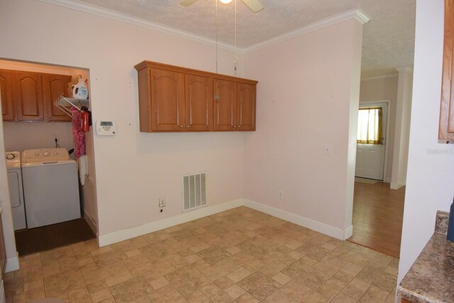 laundry room featuring ceiling fan, cabinets, a textured ceiling, washer and clothes dryer, and ornamental molding