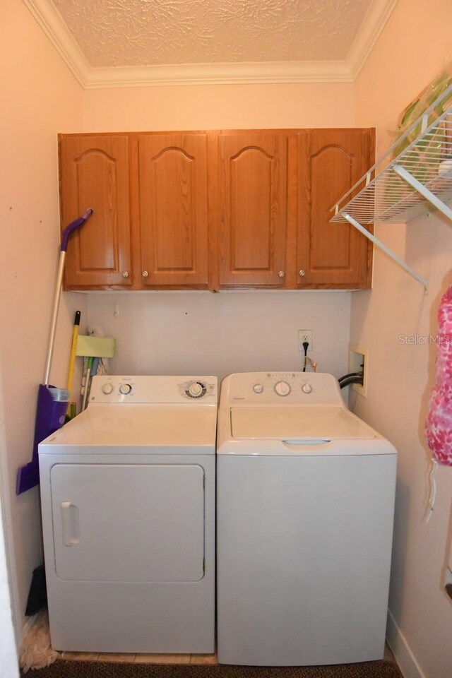 laundry area featuring cabinets, a textured ceiling, separate washer and dryer, and crown molding