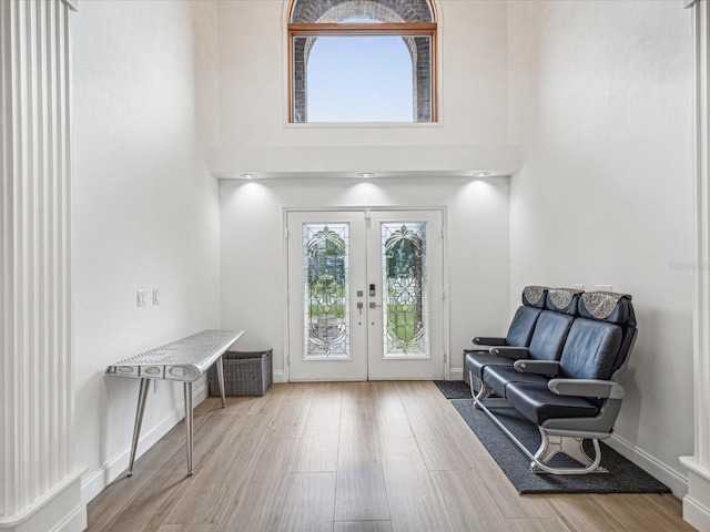 entryway with light hardwood / wood-style floors, a towering ceiling, and french doors