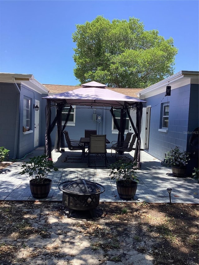 back of property with a gazebo, a patio, and a fire pit