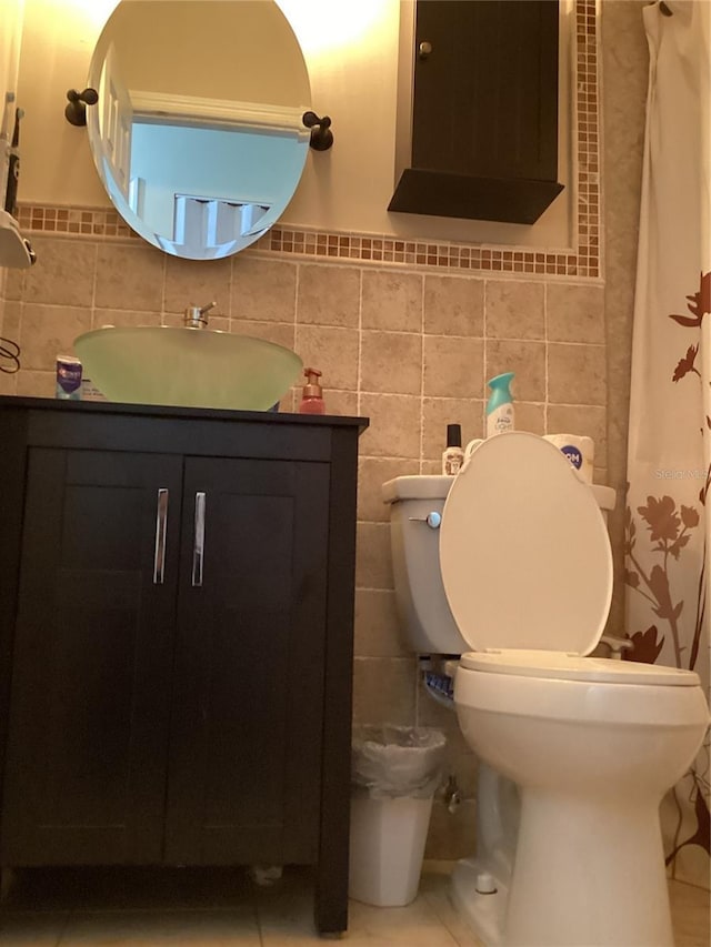 bathroom featuring tile patterned flooring, sink, toilet, and tile walls