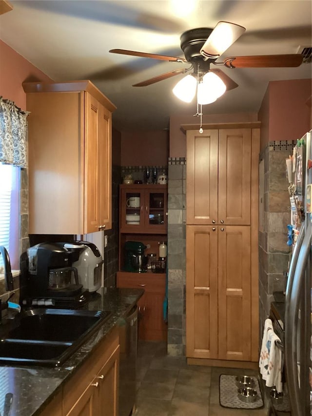 kitchen with dark stone countertops, ceiling fan, sink, and stainless steel dishwasher