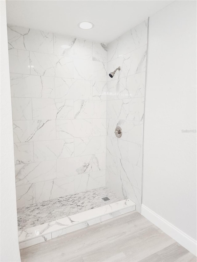 bathroom featuring a tile shower and hardwood / wood-style floors