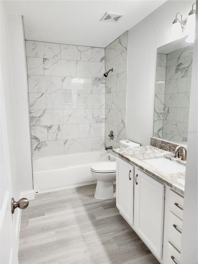 full bathroom featuring vanity, hardwood / wood-style flooring, toilet, and tiled shower / bath