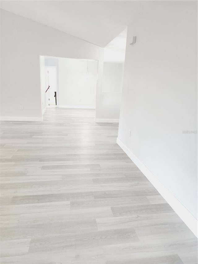 empty room with lofted ceiling and light wood-type flooring