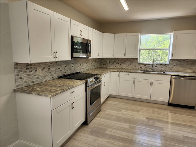 kitchen featuring backsplash, sink, appliances with stainless steel finishes, light stone counters, and white cabinetry