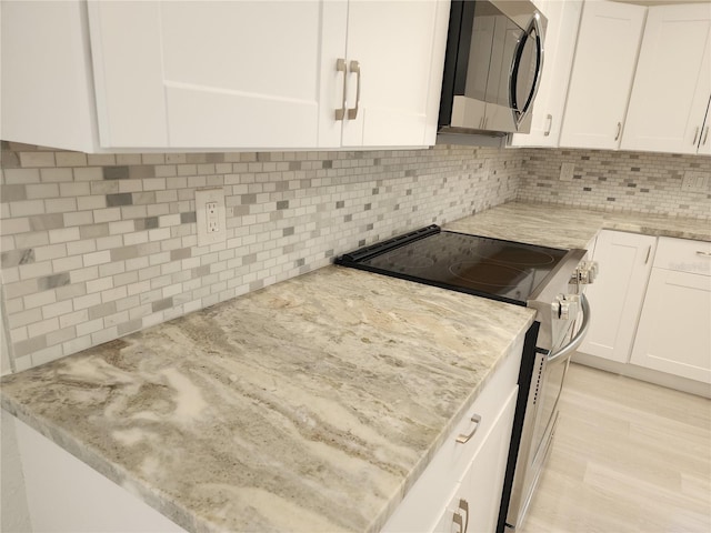 kitchen featuring stainless steel appliances, tasteful backsplash, light stone counters, white cabinets, and light wood-type flooring