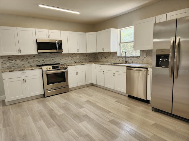 kitchen featuring backsplash, white cabinets, sink, appliances with stainless steel finishes, and light stone counters