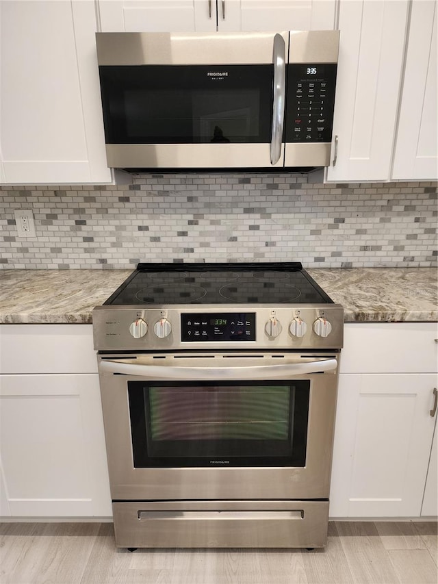 kitchen featuring decorative backsplash, white cabinetry, light stone countertops, and stainless steel appliances