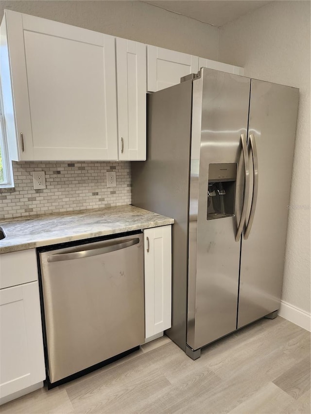 kitchen featuring backsplash, light hardwood / wood-style floors, white cabinetry, and stainless steel appliances