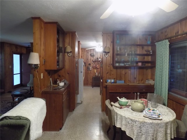 dining area with wooden walls and ceiling fan