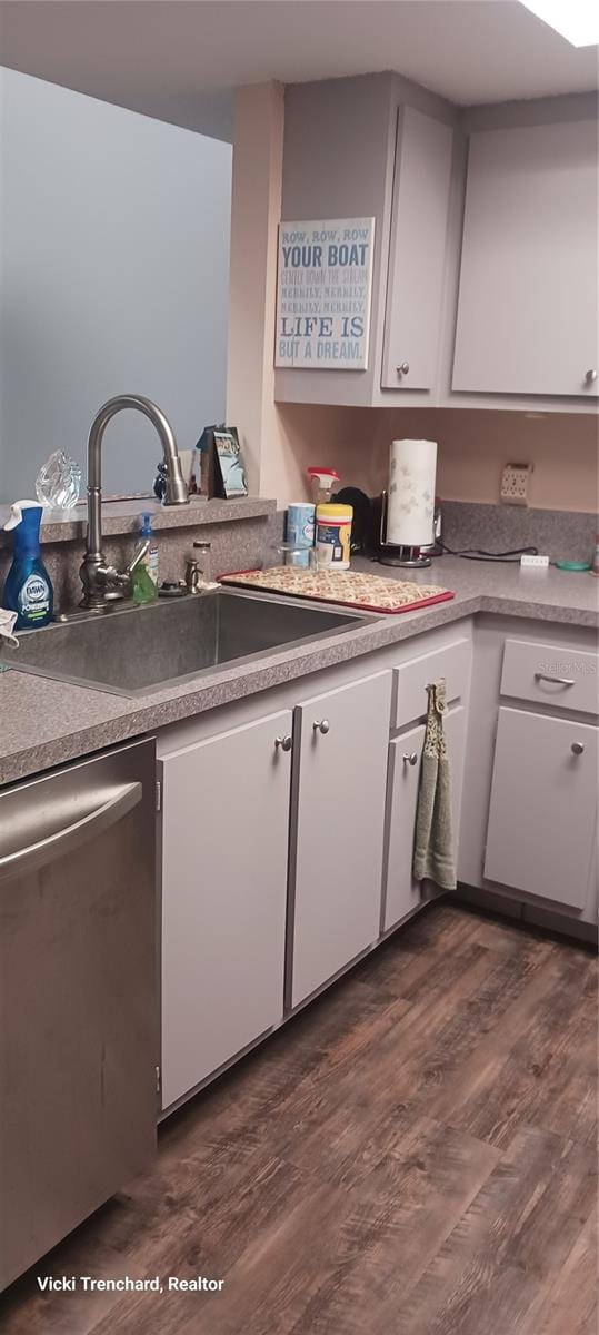 kitchen featuring stainless steel dishwasher, sink, white cabinetry, and dark wood-type flooring