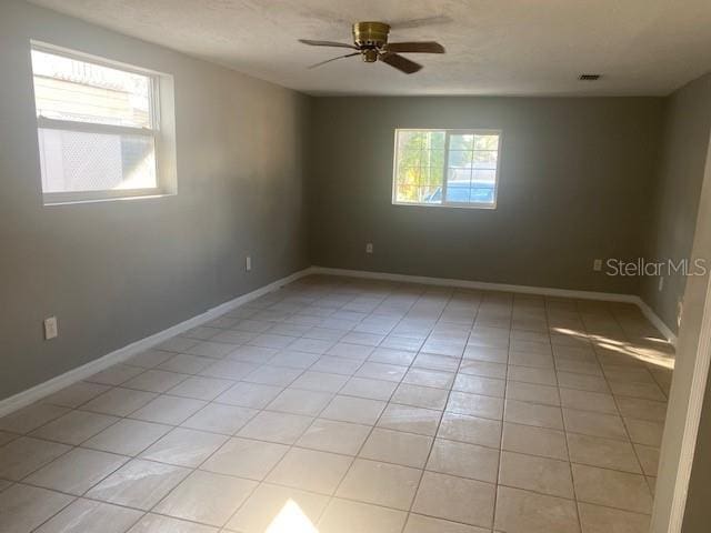 tiled spare room with a wealth of natural light and ceiling fan