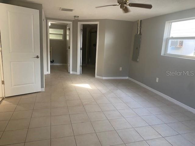 unfurnished bedroom with ceiling fan, light tile patterned floors, a spacious closet, and electric panel