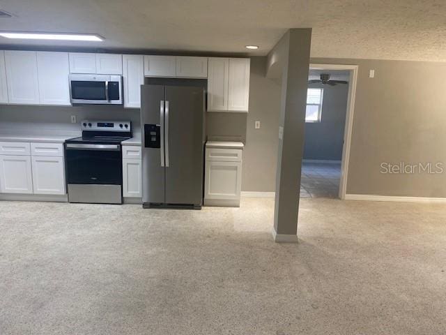 kitchen with white cabinets, ceiling fan, light colored carpet, and stainless steel appliances