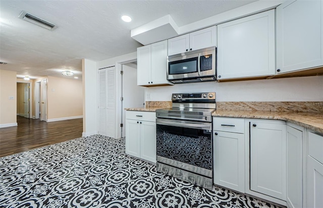 kitchen featuring light stone counters, stainless steel appliances, hardwood / wood-style floors, and white cabinets