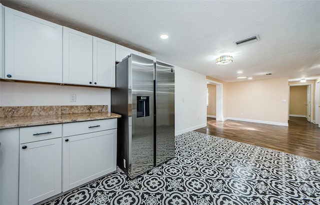 kitchen with tile floors, white cabinets, stainless steel refrigerator with ice dispenser, and light stone counters