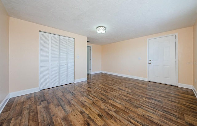 unfurnished bedroom with a textured ceiling, dark wood-type flooring, and a closet