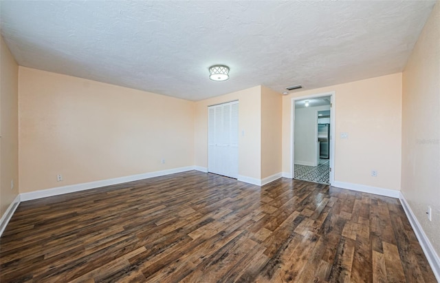 spare room featuring dark hardwood / wood-style floors and a textured ceiling