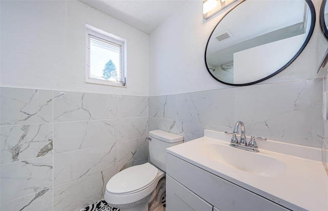 bathroom with tile walls, toilet, and vanity with extensive cabinet space