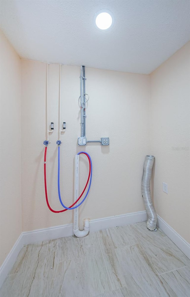 clothes washing area featuring hookup for a washing machine and a textured ceiling