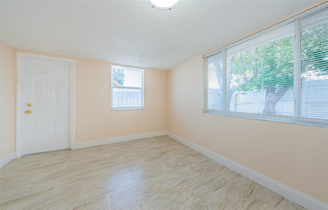 empty room with a textured ceiling and light tile floors