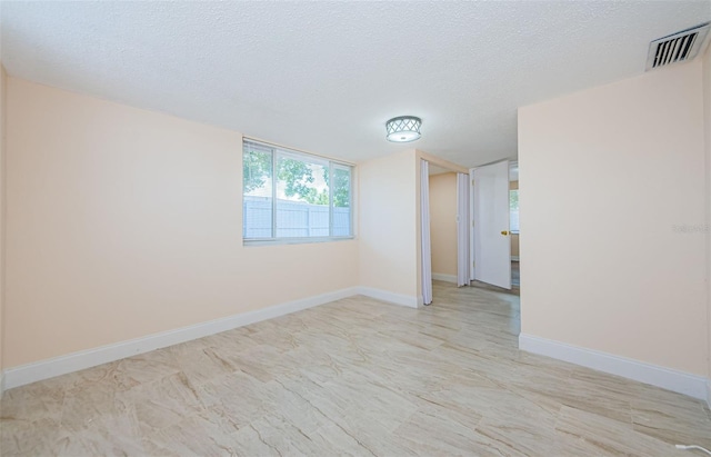 empty room featuring a textured ceiling and light tile floors