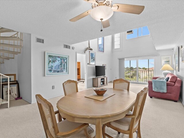 dining area featuring ceiling fan, a textured ceiling, and light colored carpet