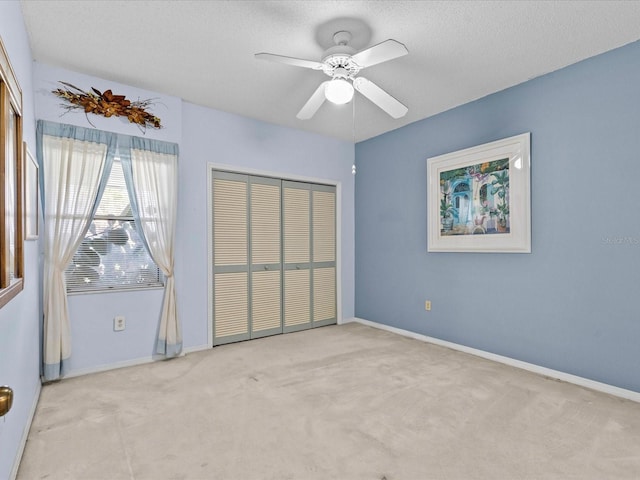 unfurnished bedroom with a textured ceiling, a closet, baseboards, and light colored carpet