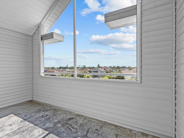 empty room featuring lofted ceiling and a residential view