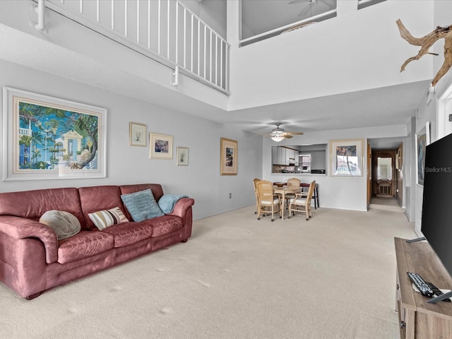 living room featuring light colored carpet, ceiling fan, and a high ceiling