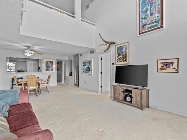 carpeted living room with a towering ceiling and ceiling fan