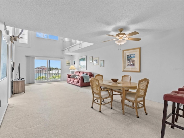 carpeted dining space with a textured ceiling and ceiling fan