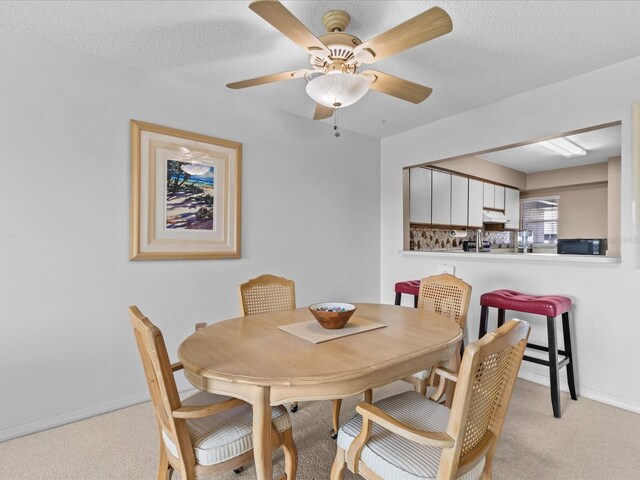 carpeted dining space featuring ceiling fan and a textured ceiling