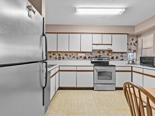 kitchen featuring tasteful backsplash, a textured ceiling, appliances with stainless steel finishes, white cabinetry, and premium range hood