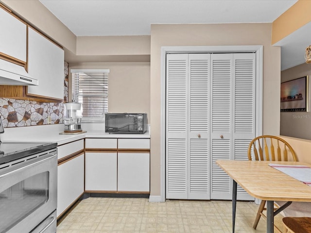 kitchen with electric range, light tile patterned flooring, white cabinets, decorative backsplash, and custom range hood