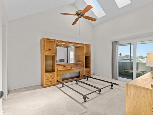 bedroom featuring ceiling fan, access to exterior, a skylight, high vaulted ceiling, and light colored carpet