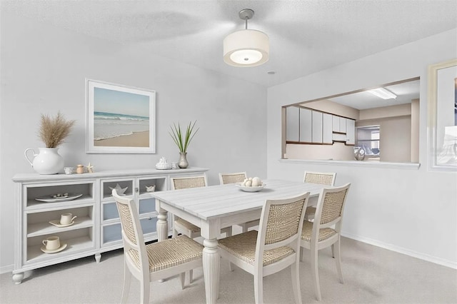 dining space with light carpet, a textured ceiling, and baseboards