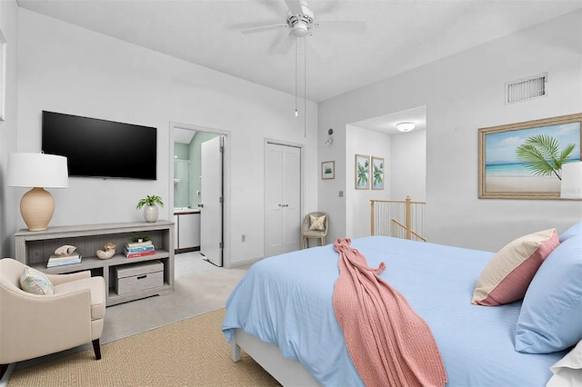 bedroom with a closet, visible vents, light carpet, ceiling fan, and ensuite bath