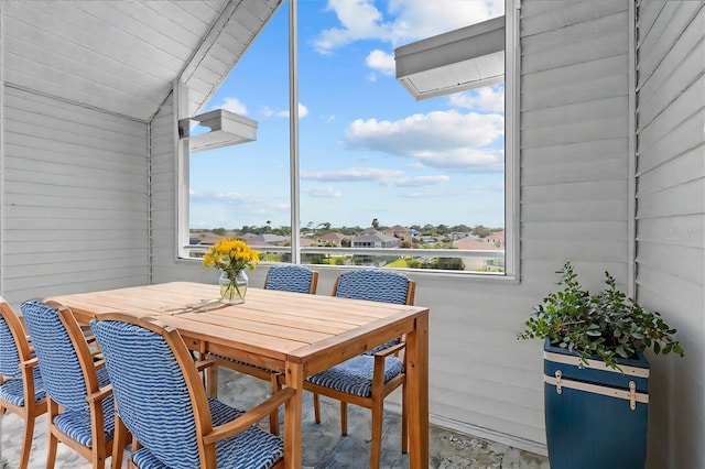 dining area with lofted ceiling and wooden walls